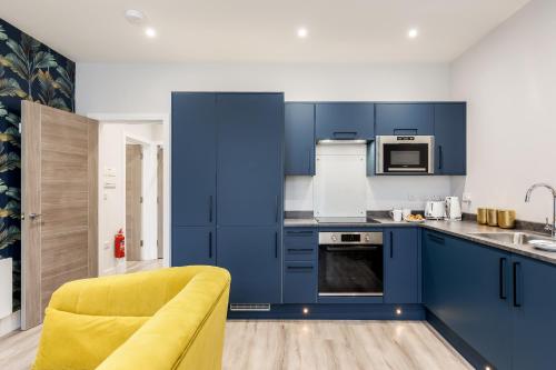 a kitchen with blue cabinets and a yellow couch at Sea Breeze - Coast in Bournemouth