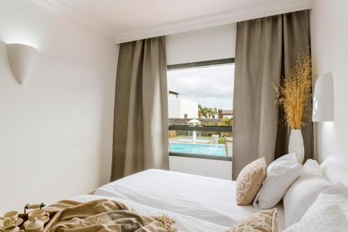 een slaapkamer met een bed en een raam met een zwembad bij Villa Marabú in Playa Blanca