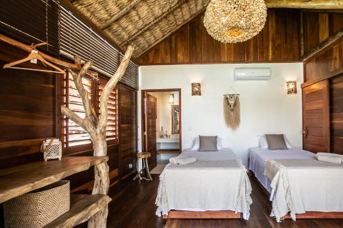two beds in a room with wooden walls and a chandelier at Rancho Noé Cumbuco in Cumbuco