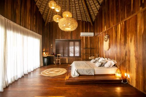 a bedroom with wooden walls and a bed and a chandelier at Rancho Noé Cumbuco in Cumbuco