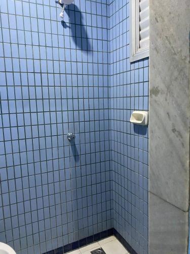 a bathroom with a shower with blue tiled walls at Hotel Angely in Belo Horizonte