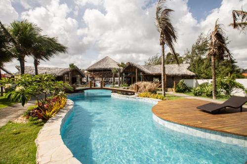 a swimming pool with a wooden deck and a resort at Rancho Noé Cumbuco in Cumbuco