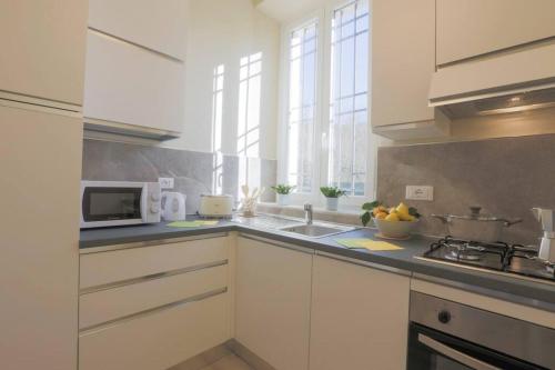a white kitchen with a sink and a microwave at [*ViLLA GiUSTi LiBERTY HOME*] SPA BBQ Wifi Parking in Lucca