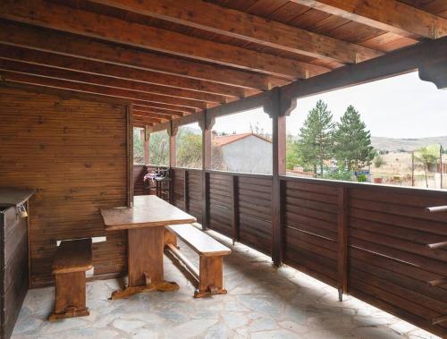 eine Holzterrasse mit einer Bank und einem großen Fenster in der Unterkunft Traditional cosy chalet in Livadi in Kalívia