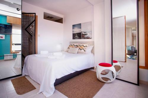 a white bedroom with a large bed and a mirror at Centro, playa y puesta de sol in A Coruña