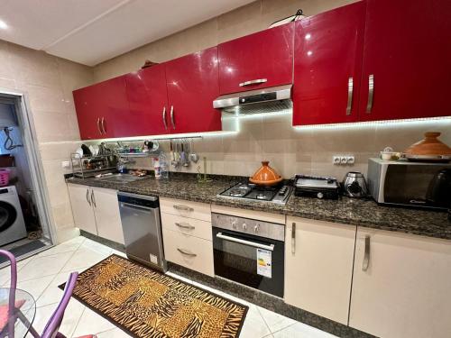 - une cuisine avec des placards rouges et une cuisinière dans l'établissement Ibtissam home, à Kenitra