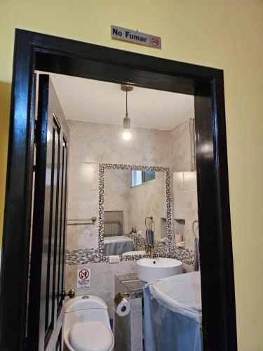 a bathroom with a toilet and a sink and a mirror at Blanca Apartments in Guayaquil