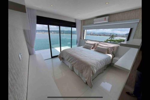 a bedroom with a bed with a view of the ocean at Mansão com vista cinematográfica pro mar! in Guarujá