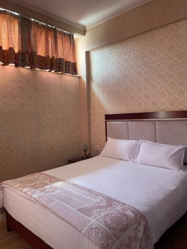 a bedroom with a large bed with white sheets at Bocca Hotel Korce in Korçë