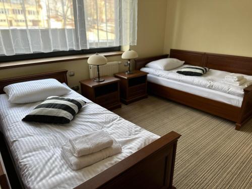two beds in a room with two lamps and towels at GLORIETTA Apartments & SPA in Iwonicz-Zdrój