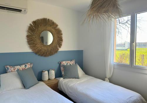 une chambre avec deux lits et un miroir au mur dans l'établissement Douce Évasion, à Biscarrosse