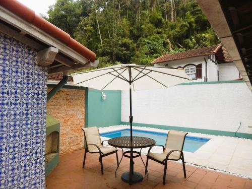 une terrasse avec une table, des chaises et un parasol dans l'établissement Refúgio da Serra, à Petrópolis