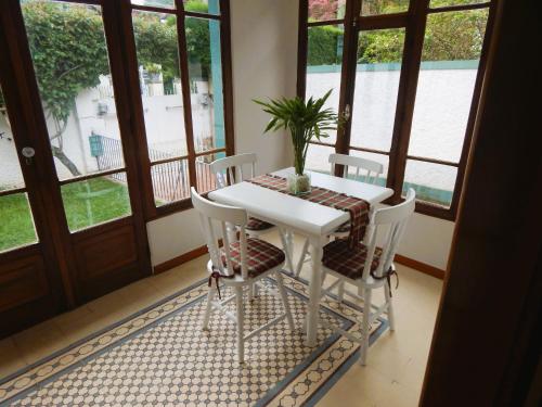 uma mesa branca e cadeiras num quarto com janelas em Refúgio da Serra em Petrópolis