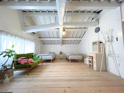 sala de estar con sofá verde y cama en ゲストハウスでたらめ荘, en Yamakami
