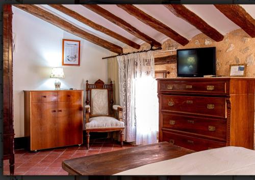 um quarto com uma cómoda, uma televisão e uma cadeira em Casa Valor em Penáguila