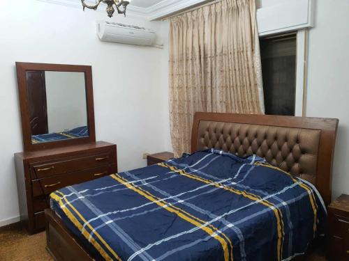 a bedroom with a bed and a mirror and a dresser at Noor Apartment in Amman