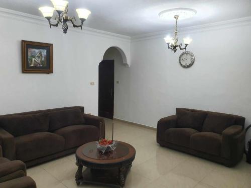 a living room with two couches and a clock on the wall at Noor Apartment in Amman
