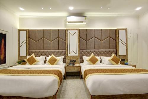 a hotel room with two beds and a large headboard at BLESS INN - Near Connaught Place in New Delhi