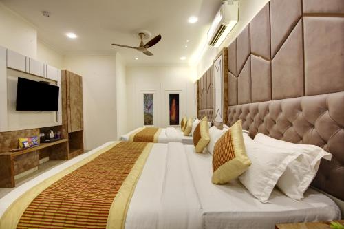 a bedroom with two beds and a flat screen tv at BLESS INN - Near Connaught Place in New Delhi