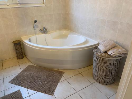 a white bath tub in a bathroom with a basket at Gîte Le Chalet Suisse Dion in Beauraing