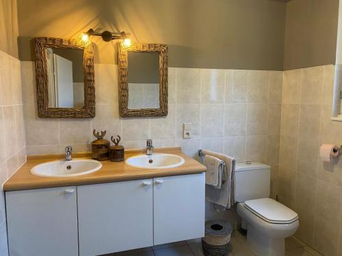 a bathroom with two sinks and a toilet and mirrors at Gîte Le Chalet Suisse Dion in Beauraing