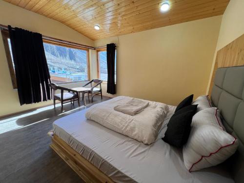 a bedroom with a bed with a table and a desk at Ashina Eco Resort in Kargil