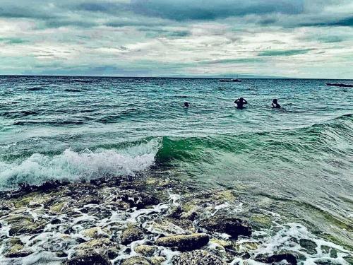 a group of people swimming in the ocean at Samantha's Cove Priv Beach House in Oslob