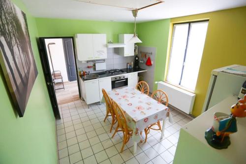 een keuken met een tafel en een keuken met groene muren bij F3 80 m2 Longére plain pied au centre auxonne. in Auxonne