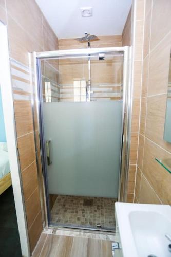 une douche avec une porte vitrée dans une salle de bain dans l'établissement F3 80 m2 Longére plain pied au centre auxonne., à Auxonne