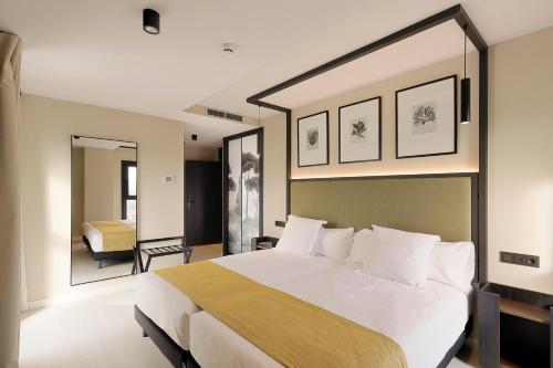 a bedroom with a large white bed and a mirror at Nuvō Hotel Boutique in Oviedo