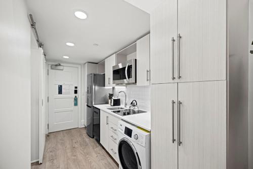a kitchen with white cabinets and a washer and dryer at Placemakr Dupont Circle in Washington