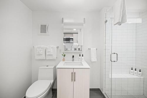 a white bathroom with a toilet and a sink at Placemakr Dupont Circle in Washington