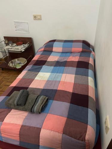 a bed with a colorful plaid blanket on it at Habitacion doble en Figueres in Figueres