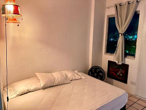 a bedroom with a white bed with a window at Suite aconchegante na Torre in Recife