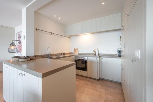 a large kitchen with white cabinets and a sink at Appartement 7 op de zeedijk in Knokke voor max 6 personen in Knokke-Heist