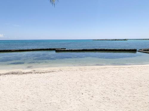 a swimming pool on a beach next to the ocean at Beachfront Breathtaking Views Puerto Aventuras in Puerto Aventuras