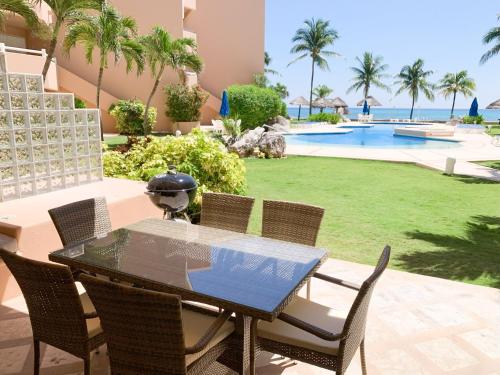 a patio with a table and chairs and a pool at Beachfront Breathtaking Views Puerto Aventuras in Puerto Aventuras