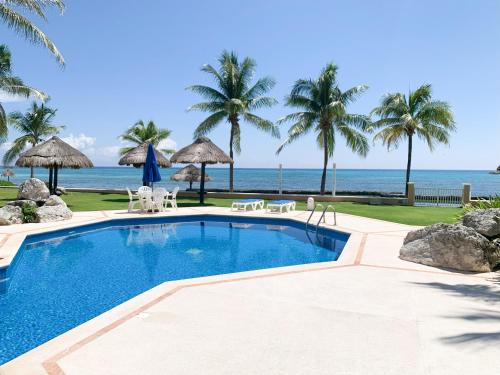 a swimming pool with the beach in the background at Beachfront Breathtaking Views Puerto Aventuras in Puerto Aventuras