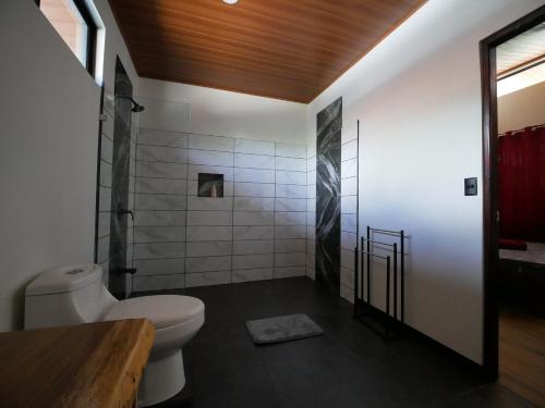 La salle de bains est pourvue d'une douche et de toilettes blanches. dans l'établissement Raya, à Matapalo