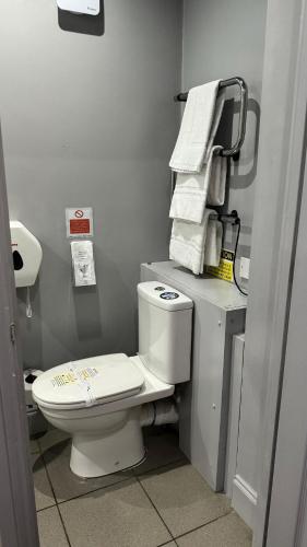 a bathroom with a toilet and towels on a shelf at The Railway Sleeper Lodge in Colchester