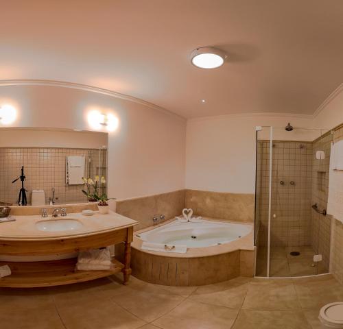 a bathroom with a tub and two sinks and a shower at Hotel Solar d'Izabel in Campos do Jordão