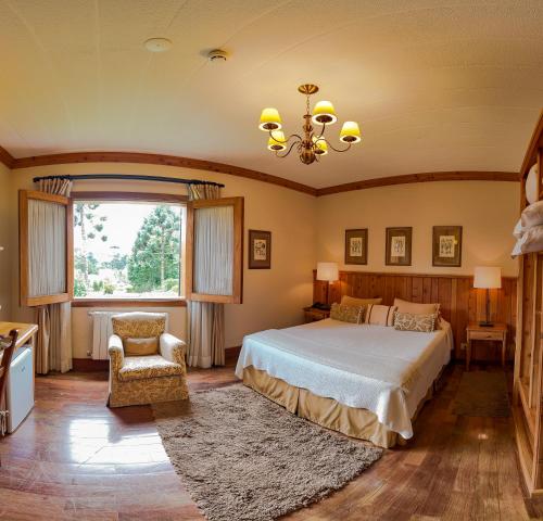 um quarto com uma cama, uma cadeira e uma janela em Hotel Solar d'Izabel em Campos do Jordão