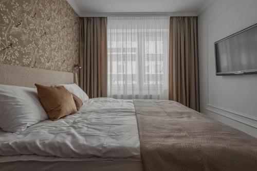 a bedroom with a large bed and a flat screen tv at Puodžių 5 - Self check in, , City center in Klaipėda