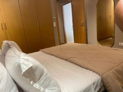 una camera da letto con un letto con lenzuola bianche e uno specchio di Appartement a tunis a Tunisi