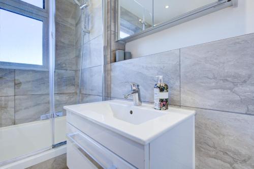 a bathroom with a white sink and a shower at Exquisite 5-Bedroom in London and Essex - Sleeps 10 with Free Parking in Romford