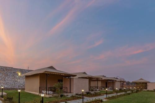 a row of lodges with a rainbow in the sky at Sterling ReWild Sariska in Tehla