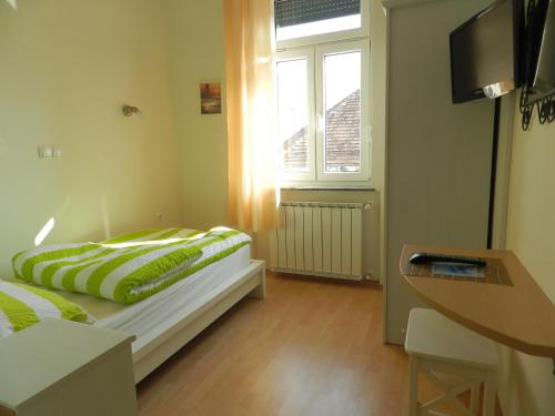 a bedroom with a bed with green pillows and a window at Hostel Sonce in Ptuj