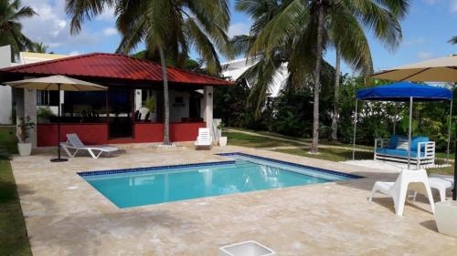 una piscina con sillas y sombrillas junto a una casa en VILLA BOCA MAR, en Boca Chica