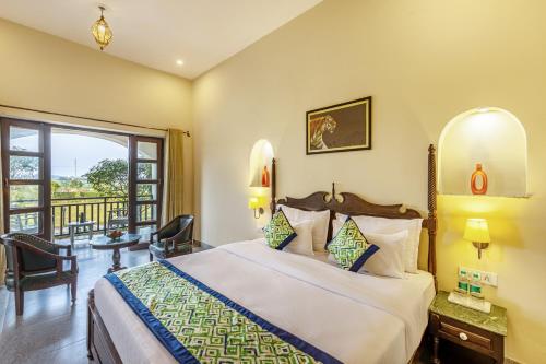 a bedroom with a large bed and a balcony at Sterling ReWild Sariska in Tehla