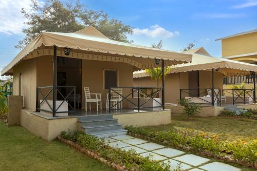 a house with a porch with a table and chairs at Sterling ReWild Sariska in Tehla